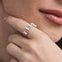 Close-up of a hand wearing a pearl ring with a blurred background