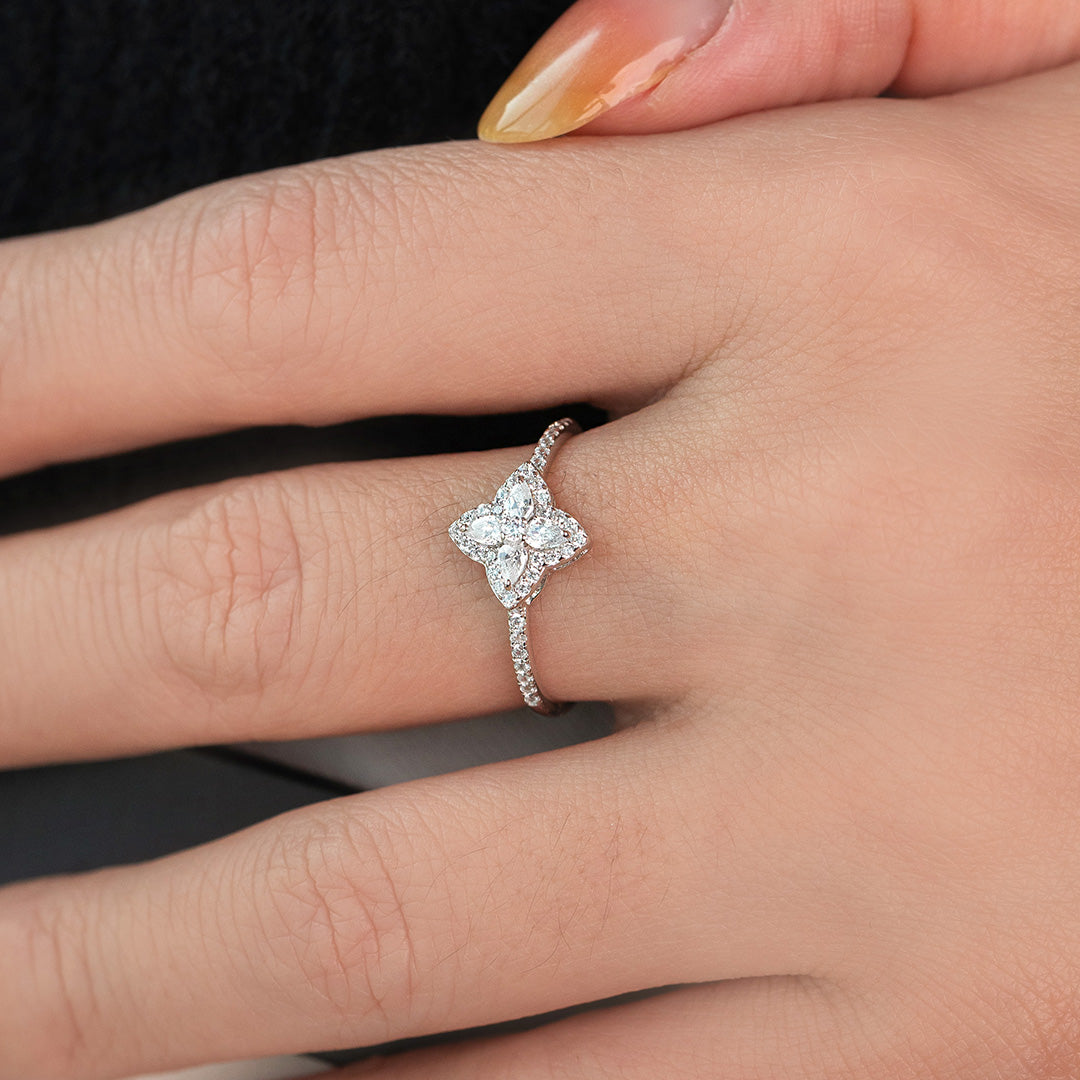 A gold-colored band ring with zircon stones and a mother pearl stone on the band, displayed on a person's finger.