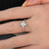 A gold-colored band ring with zircon stones and a mother pearl stone on the band, displayed on a person's finger.