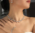 Close-up of a woman wearing a diamond necklace, earrings, and bracelet against a dark background.