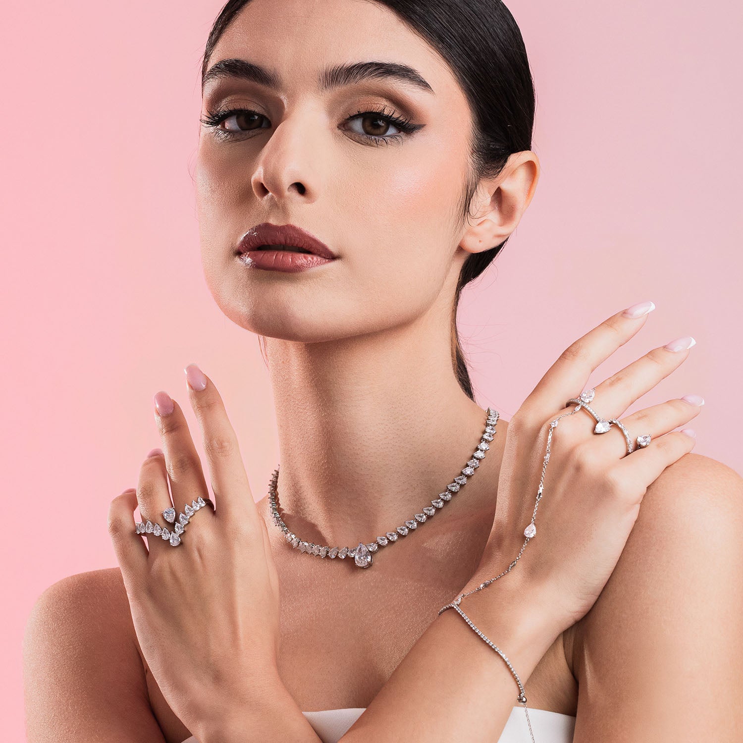 Woman wearing diamond jewelry against a pink background
