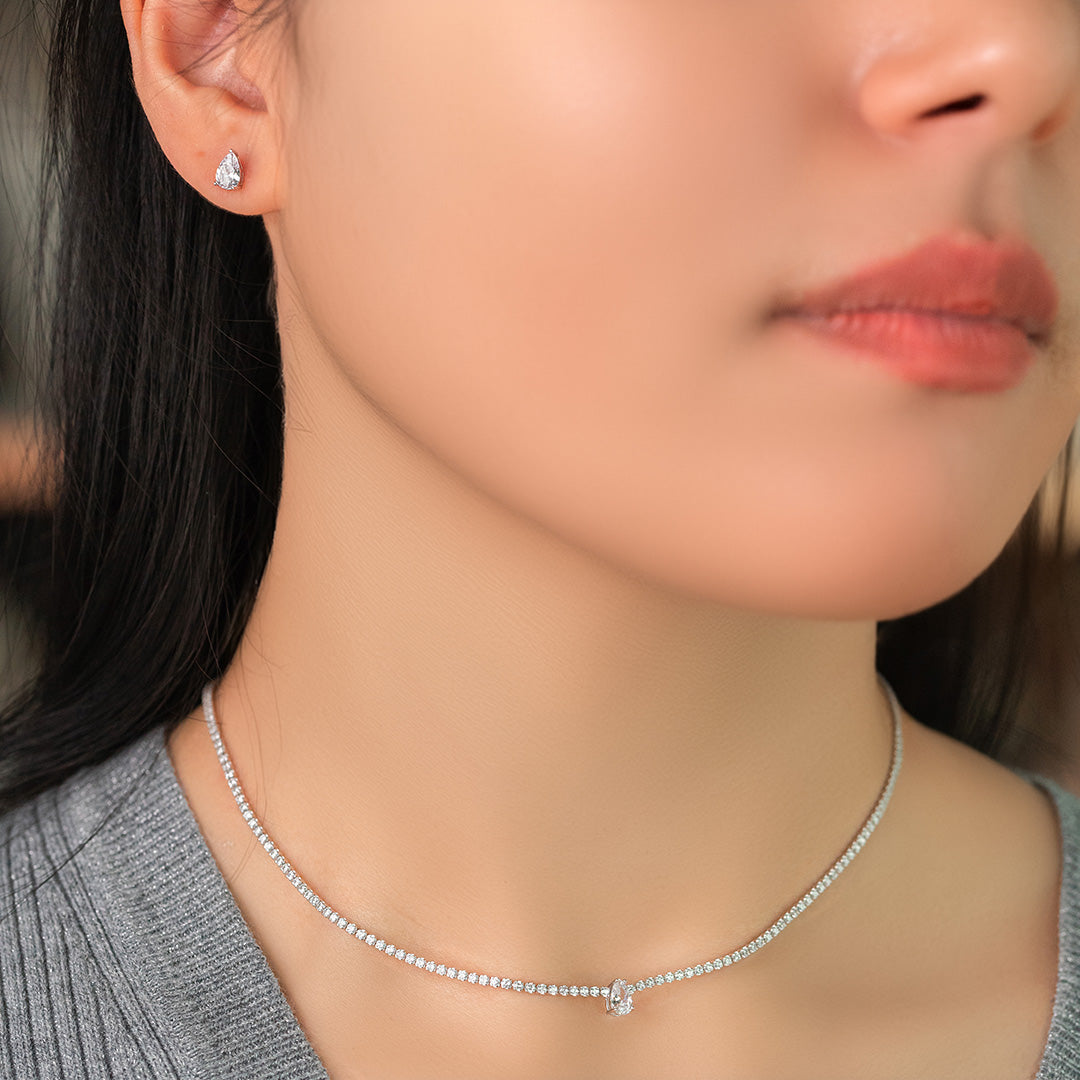 A close-up image of a woman wearing a silver choker necklace with a gold plating and zircon stones.