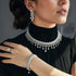 A person wearing a rhodium-plated necklace set with zircon stones, consisting of a long necklace and a pair of earrings.