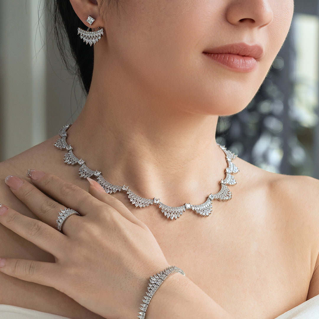 Woman wearing a silver necklace, earrings, and bracelet with a blurred background